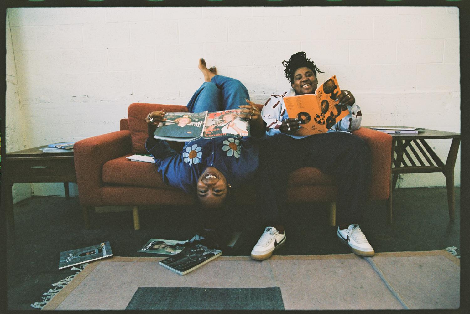 Two people reading magazines on a couch